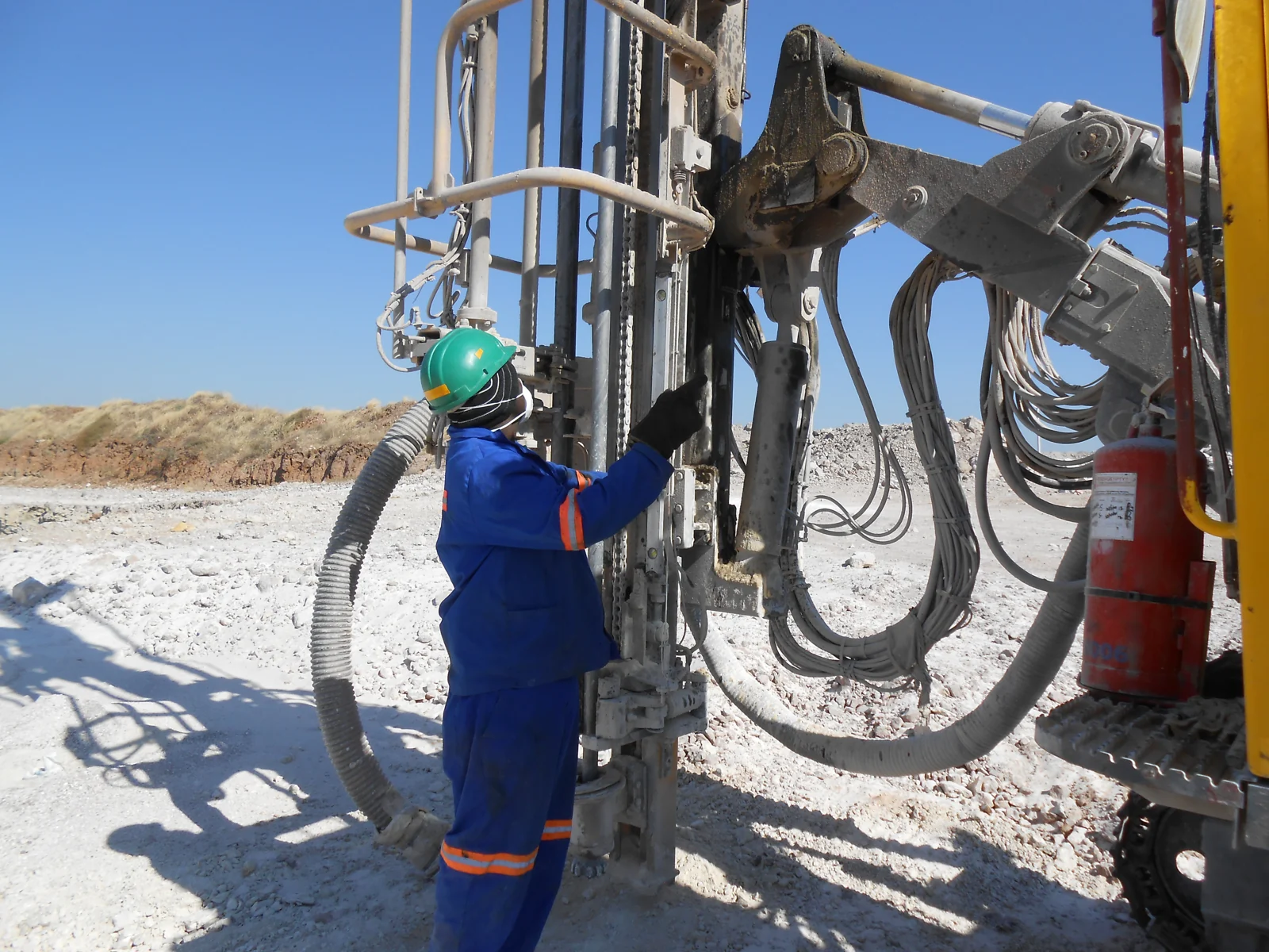 A worker operating a drilling rig at an industrial site